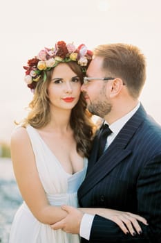 Groom hugs bride by the waist and looks into her face. High quality photo