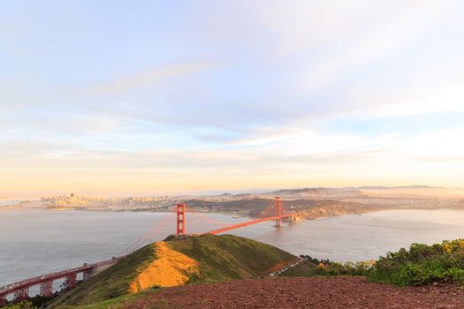 Red suspension bridge with city of San Francisco in distance at golden hour. High quality photo