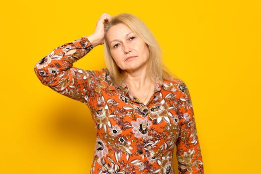 Woman scratching her head with doubts and confusion isolated on yellow background. Idea, hair scratch and difficult choice for model in studio with frustrated expression on her face