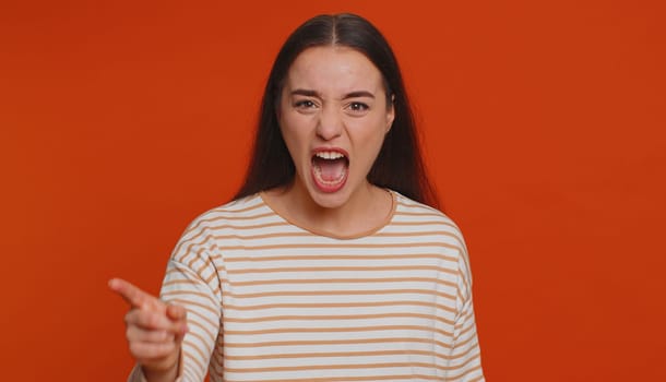 Quarrel. Displeased pretty young woman gesturing hands with irritation and displeasure, blaming scolding for failure, asking why this happened. Millennial girl isolated on red studio background