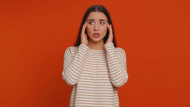 Hipster young pretty woman in pullover rubbing temples to cure headache problem, suffering from tension, migaine, stress, grimacing in pain, high blood pressure isolated alone on red wall background