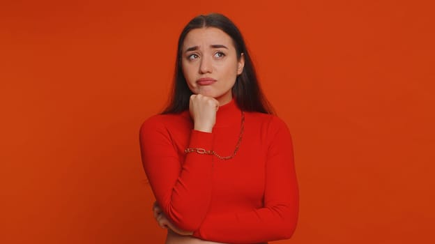 Sad tired bored pretty woman indifferent expression, exhausted of tedious story, not interested in communication talk, displeasure, uninteresting. Young girl isolated alone on red studio background