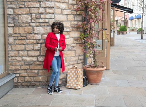 Happy confident smiling curvy african american woman with shopping bags standing on city street near shop windows. High quality photo