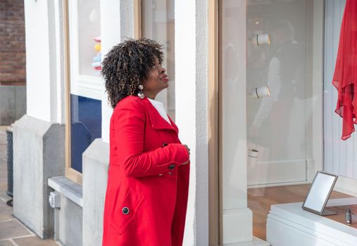 Happy confident smiling curvy african american woman with shopping bags standing on city street near shop windows. High quality photo