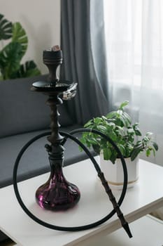 Hookah shisha with glass flask and metal bowl in room background. Traditional Eastern vacation for relaxation.