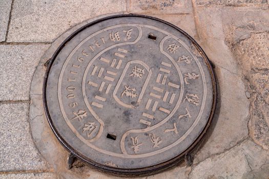A manhole cover inscribed in Chinese in the courtyard of Kumbum Champa Ling Monastery, Xining, China