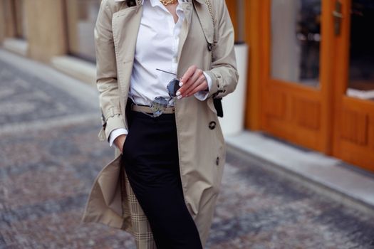 Close up stylish woman in coat with glasses crossing the city street.. High quality photo