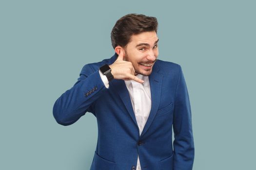 Portrait of happy positive man with mustache standing showing call me back gesture, flirting with beautiful woman, wearing official style suit. Indoor studio shot isolated on light blue background.