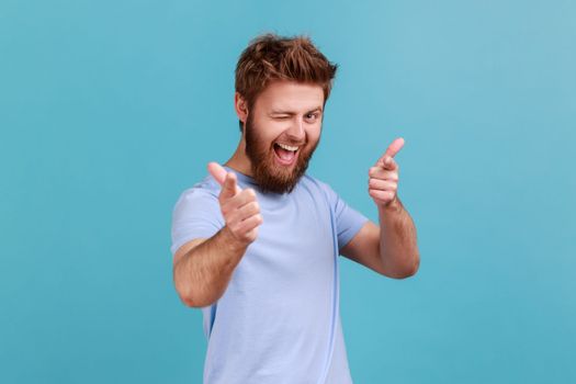 You are special. Portrait of positive happy bearded man pointing fingers at camera and looking with toothy smile, believes in you, motivation. Indoor studio shot isolated on blue background.