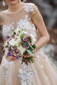 wedding bouquet with peonies in the hands of the bride under the veil.Morning of the bride.