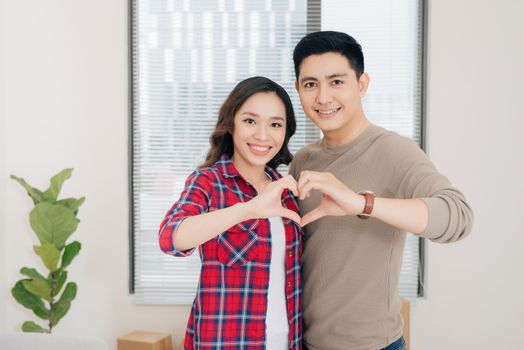 Couple relaxing during home renovation and showing heart shape gesture