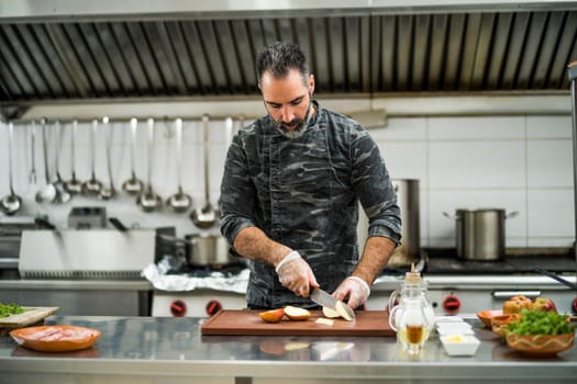 Professional cook is preparing meal in restaurant's kitchen. He is cutting apples.