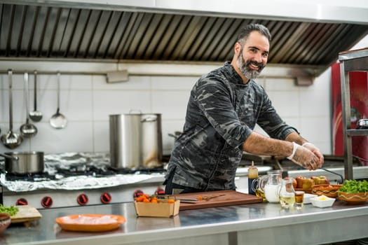 Professional cook is ready for preparing meal in restaurant's kitchen.