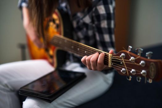 Teenage girl is playing guitar at home.