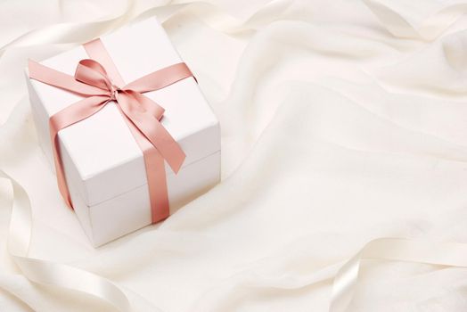 Romantic gift. Present on white silk background.