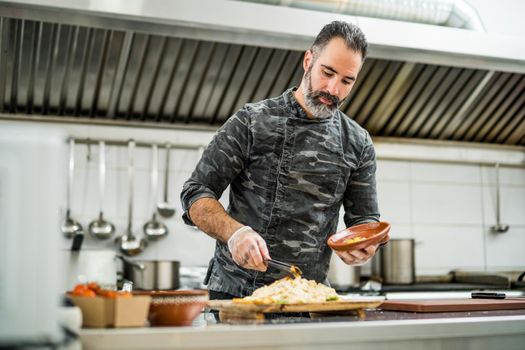 Professional cook is serving meal in restaurant's kitchen.