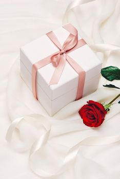 Romantic gift. Present on white silk background.