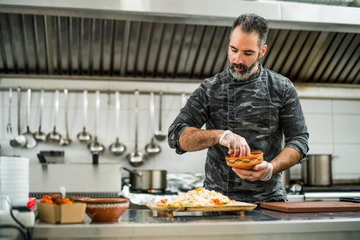 Professional cook is ready for preparing meal in restaurant's kitchen.