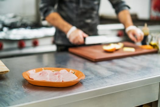 Professional cook is preparing meal in restaurant's kitchen. He is cutting apples.