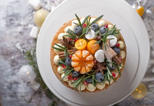 Homemade Christmas cake on rustic wooden stand and holiday decoration