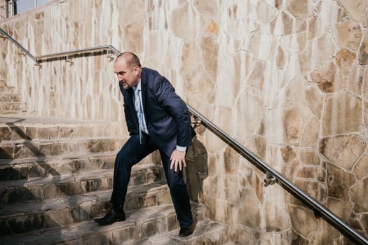 Portrait of a senior professional man in a suit with various problems. A middle-aged businessman with a briefcase descends the stairs.