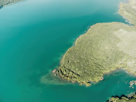 Aerial landscape from flying drone storage reservoir at mountain foot covered colorful spring forest. Beautiful view from above blue lake among highlands