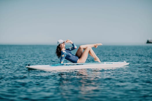 Woman sup yoga. Middle age sporty woman practising yoga pilates on paddle sup surfboard. Female stretching doing workout on sea water. Modern individual hipster outdoor summer sport activity