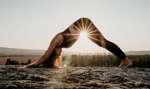 Well looking middle aged woman with long hair, fitness instructor in leggings and tops doing stretching and pilates on the rock near forest. Female fitness yoga routine concept. Healthy lifestyle.