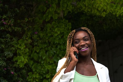 Happy Young Black woman talking on the phone outdoors. Copy space. Lifestyle and technology.