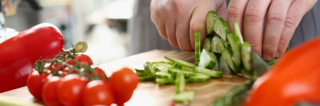 Green cucumbers are cut with knife in kitchen. Healthy food concept vegetable salad and vegetarianism