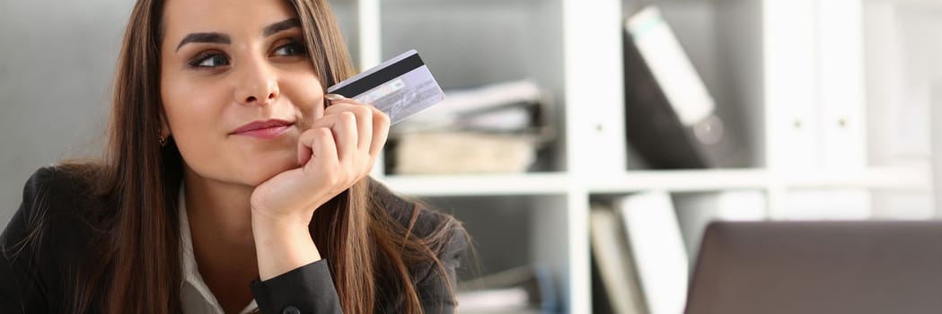 Happy pensive office worker holding bank credit card. Online shopping banking and online shopping