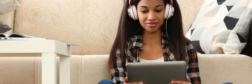 Learn foreign language online at home through application. Focused mixed race woman and remote female student sitting on floor in headset holding tablet pc