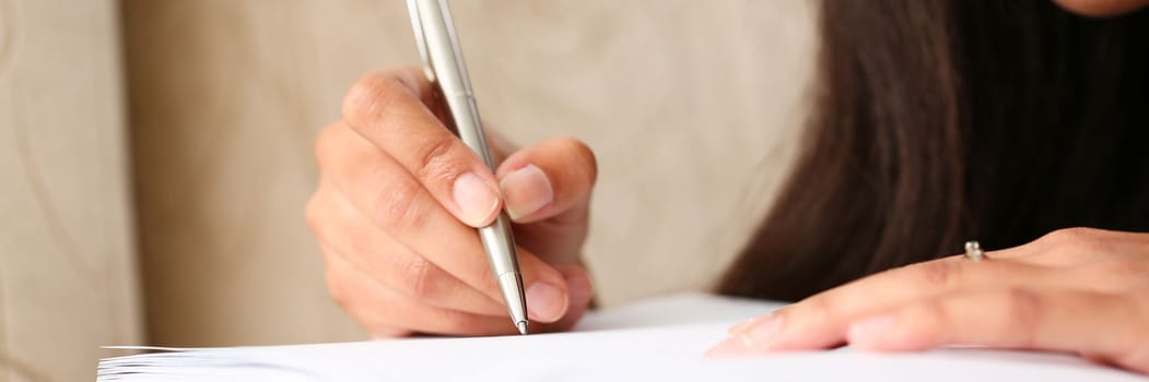 Closeup of hands of black female writer at home writing in magazine. Copywriter journalist and training concept