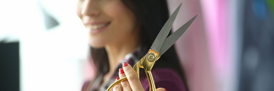 Woman smiling with scissors in hand in fashion atelier. Atelier services and tailoring concepts for a new collection of clothes