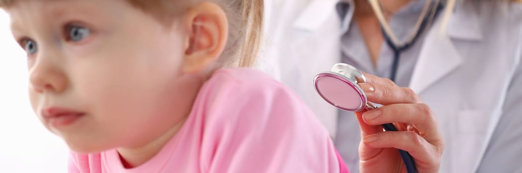 Pediatrician listens to lungs of small child girl with stethoscope. Children health insurance and examination of lungs and heart