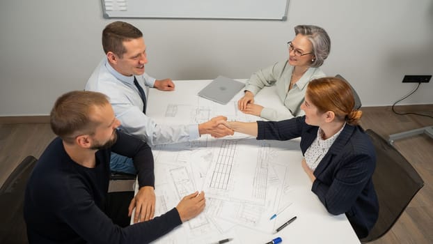 Business partners shake hands. Four business people are negotiating in the conference room