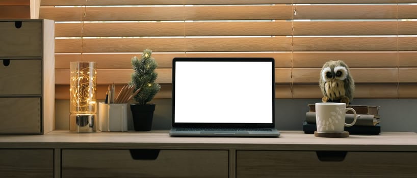 Front view laptop computer with white display on wooden counter near blinds window.
