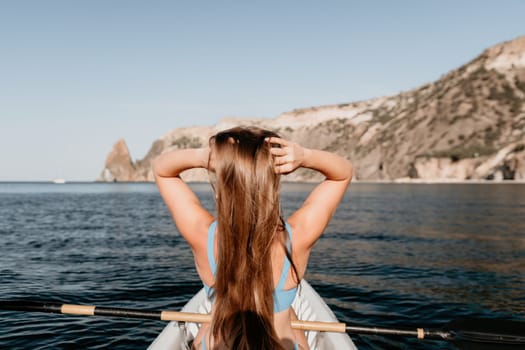 Woman in kayak back view. Happy young woman with long hair floating in transparent kayak on the crystal clear sea. Summer holiday vacation and cheerful female people relaxing having fun on the boat