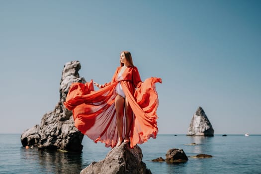 Woman travel sea. Happy tourist taking picture outdoors for memories. Woman traveler looks at the edge of the cliff on the sea bay of mountains, sharing travel adventure journey.