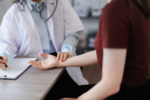 Portrait of a female doctor using a stethoscope to check the pulse of an elderly patient