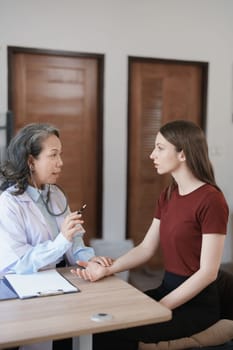 Portrait of a female doctor using a stethoscope to check the pulse of an elderly patient