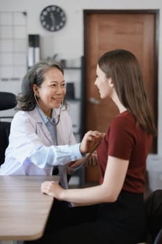 Portrait of a female doctor using a stethoscope to check the pulse of an elderly patient