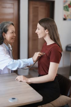 Portrait of a female doctor using a stethoscope to check the pulse of an elderly patient