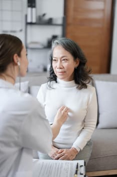 Portrait of a female doctor using a stethoscope to check the pulse of an elderly patient