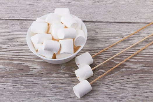 Bowl with marshmallows on a wood background