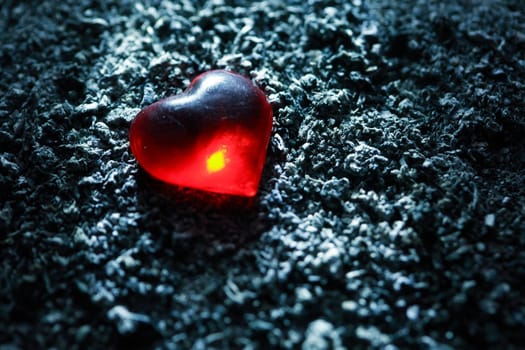 Love concept. Red glass heart on gray ash background