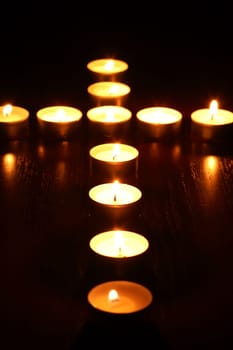 Set of lighting candles as religion cross on dark background