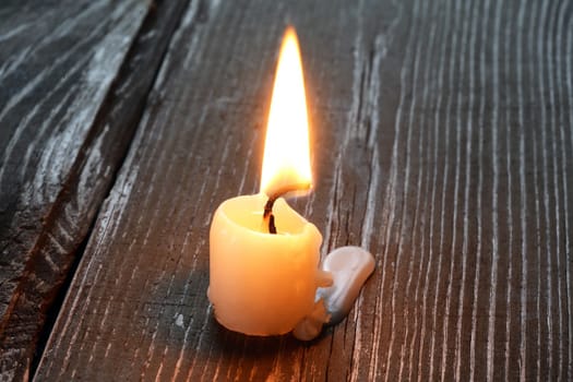 Alone lighting candle on old wooden surface