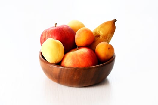 Heap of freshness fruits in wooden bowl on white background