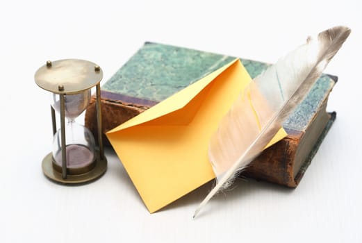 Still life with book and quill pen near empty envelope